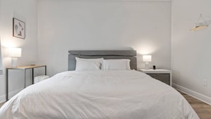 Un dormitorio moderno con una cama grande, dos mesitas de noche y una lámpara fijada a la pared.