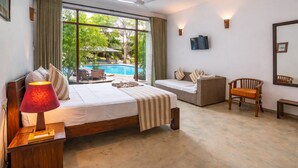 A bedroom with a bed, a desk, a chair, a TV, and a view of an outdoor swimming pool. - Tartaruga Beach Unawatuna (Unawatuna)