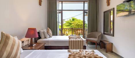 A hotel room with a bed, bedside table, lamp, chair, and a view of greenery outside.