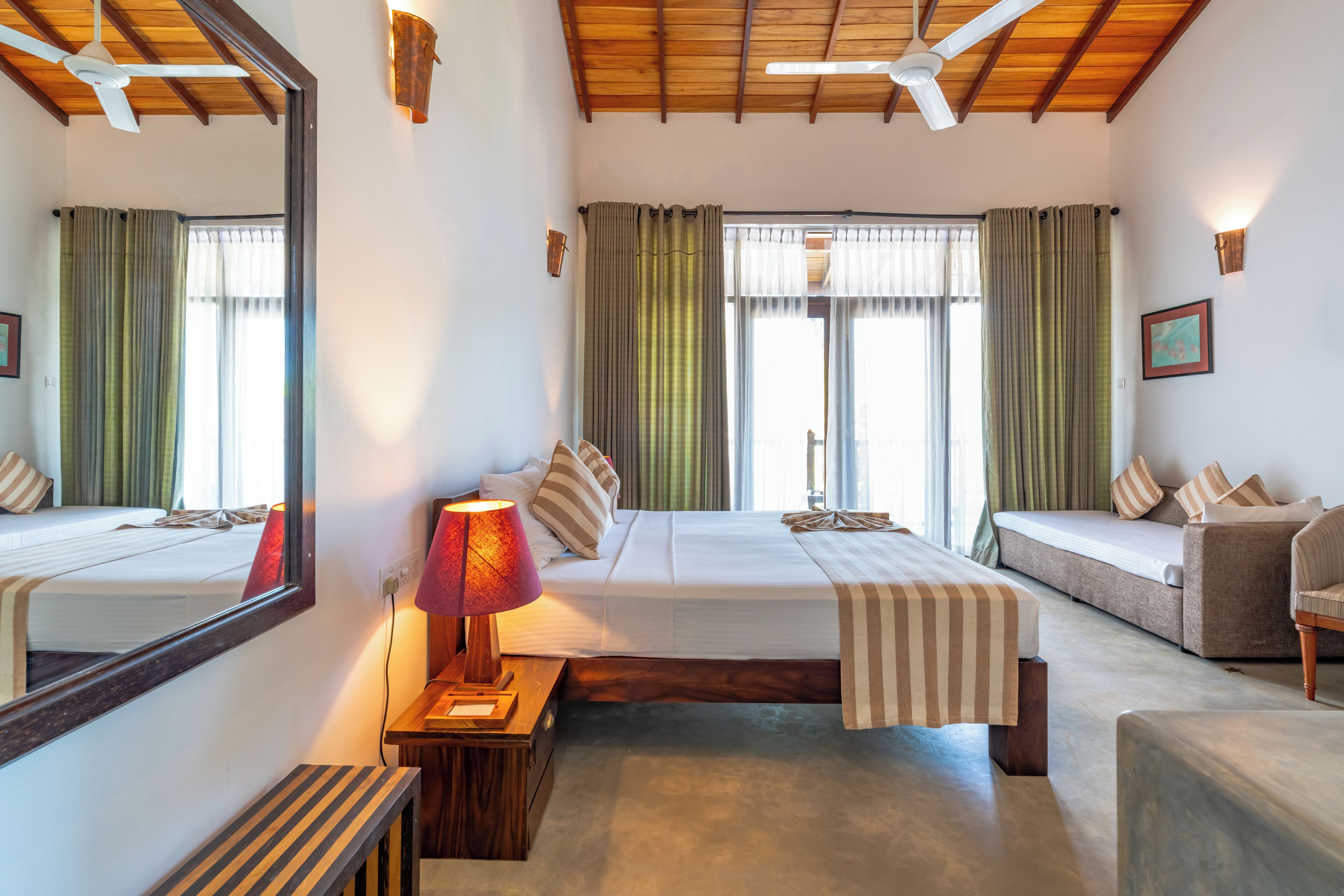 Ein Hotelzimmer mit einem großen Bett, einer Couch, einem Schreibtisch, einer Lampe und einem Spiegel.
