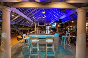 An indoor bar area with a high ceiling, bar stools, and a counter.