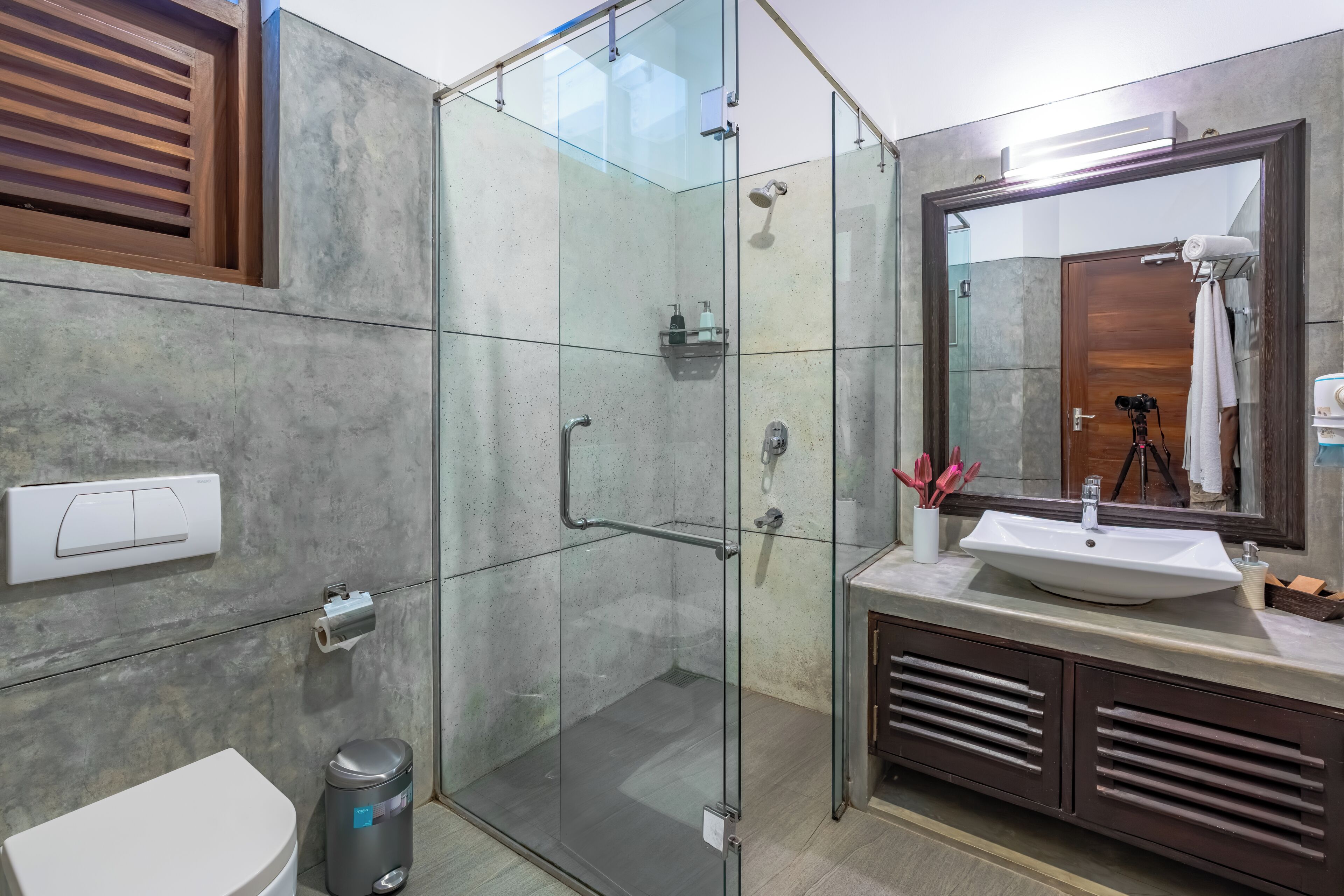 Une salle de bain moderne avec une douche à parois de verre, un lavabo avec un miroir et des toilettes.