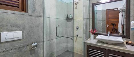 Une salle de bain moderne avec une douche à parois de verre, un lavabo avec un miroir et des toilettes.