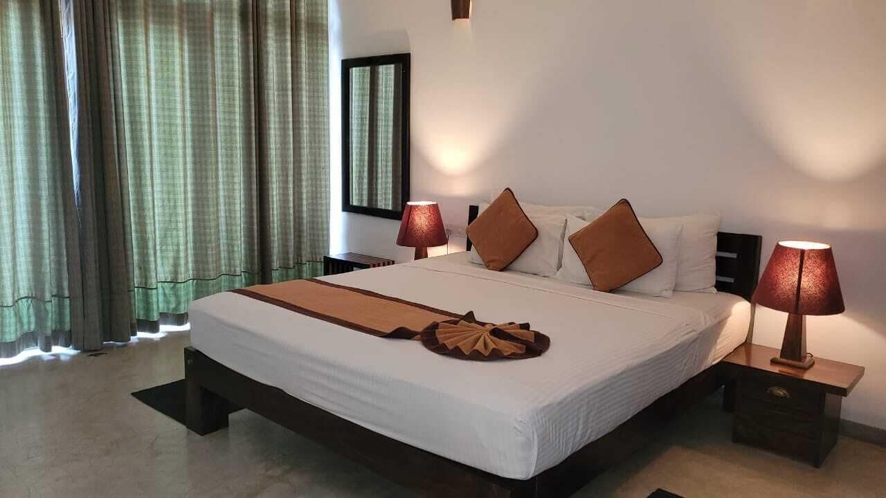 A large bed with white linens, two brown pillows, and a decorative brown headboard. There are two bedside lamps on wooden nightstands.