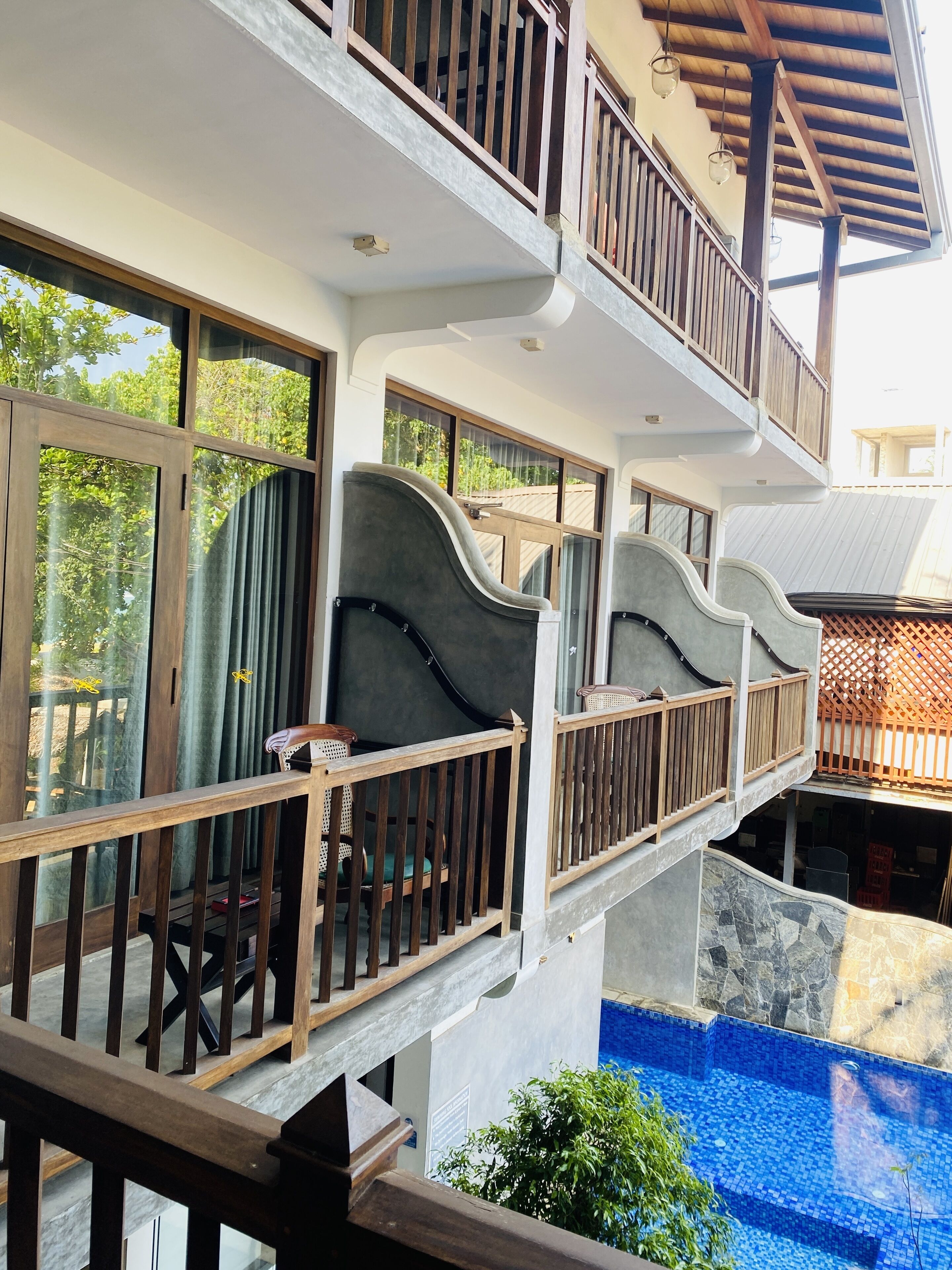 A multi-level outdoor area with a pool, wooden railings, and a seating area with a table and chairs.