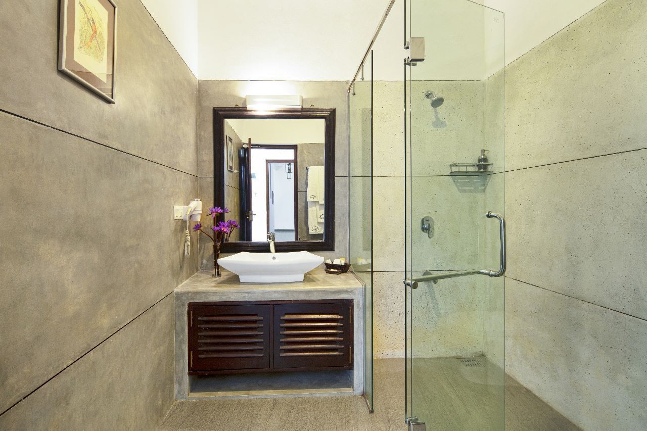 A modern bathroom with a large mirror, a sink, and a shower area.
