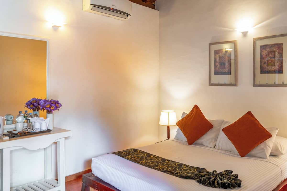Habitació d'hotel amb llit, taulell de nit, làmpada, obra d'art a la paret i mirall.