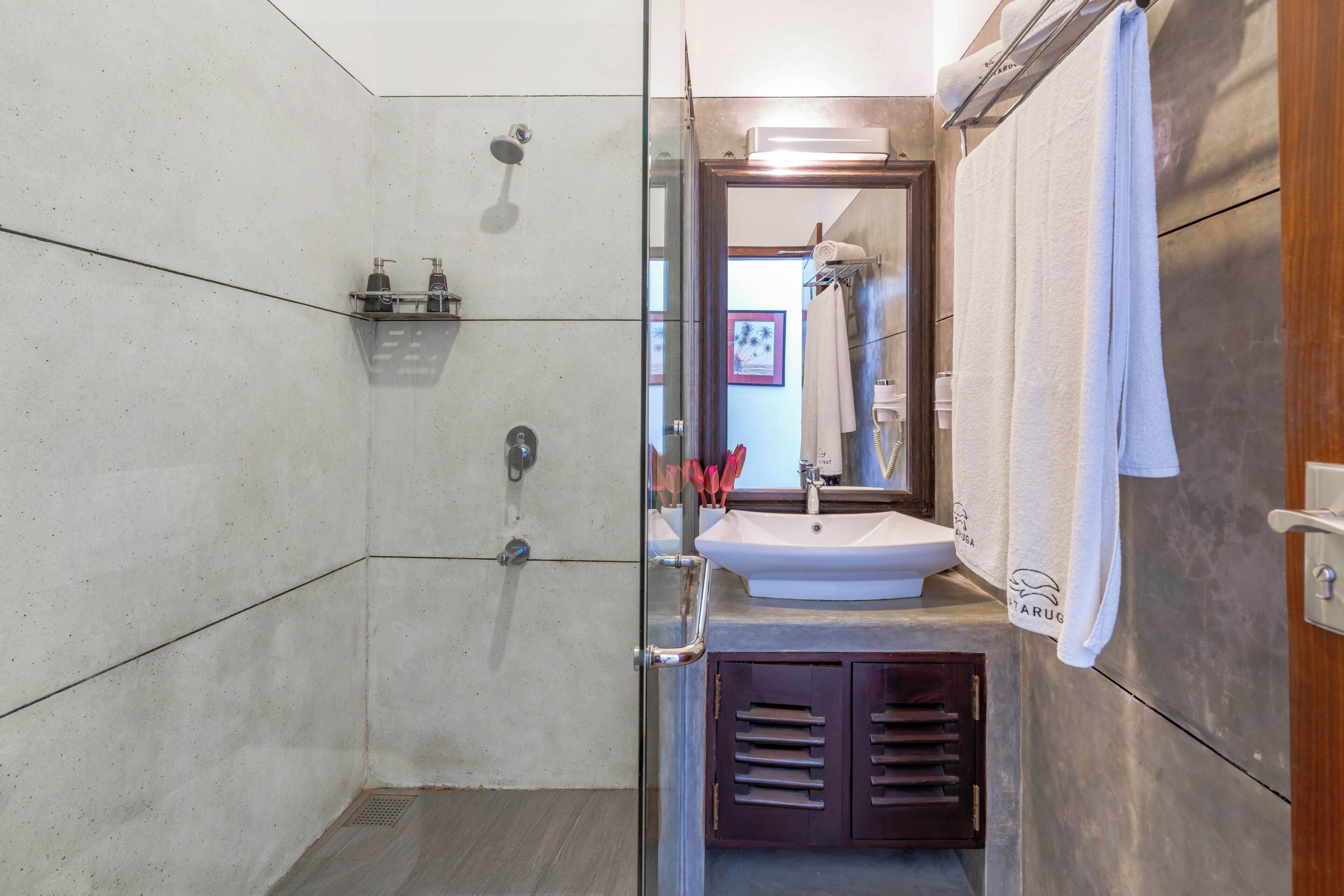 A modern bathroom with a glass shower enclosure, a sink with a mirror, and a towel rack.