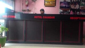 Un comptoir d’accueil à l’hôtel Chandran, avec une pancarte « Bienvenue », un tableau encadré au mur et un ventilateur.