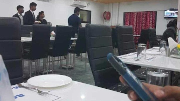 Un espace repas avec des tables dressées, un ventilateur de plafond et un appareil de climatisation.