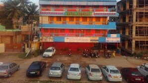 Un hôtel à plusieurs étages, doté d’une façade bleue et rouge, de nombreux balcons et d’un parking où sont stationnées plusieurs voitures.