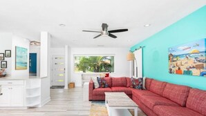 A modern living room with a red sofa, a white coffee table, and a ceiling fan. - Splash & Explore (St. Augustine)