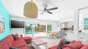 A modern living room with red sofas, a wooden coffee table, and a ceiling fan. - Splash & Explore (St. Augustine)