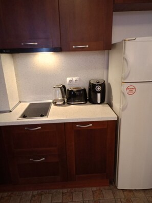 A kitchen with wooden cabinets, a white countertop, a coffee maker, a kettle, and a white refrigerator. - Mountain Paradise 1 - 1 Bedroom South Facing Balcony - 300mbps Wi-fi (Bansko)