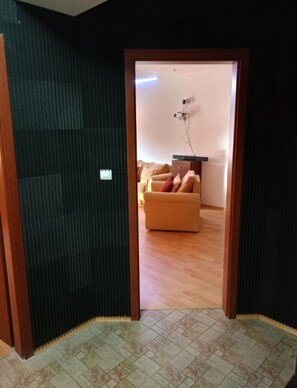 A room with a wooden floor, a sofa, and a small table. - Mountain Paradise 1 - 1 Bedroom South Facing Balcony - 300mbps Wi-fi (Bansko)