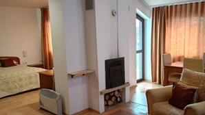 A modern living room with a wooden table, a sofa, a TV, and a fireplace. - Mountain Paradise 1 - 1 Bedroom South Facing Balcony - 300mbps Wi-fi (Bansko)