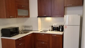 A compact kitchen with wooden cabinets, a white refrigerator, a microwave, and a coffee maker. - Mountain Paradise 1 - 1 Bedroom South Facing Balcony - 300mbps Wi-fi (Bansko)