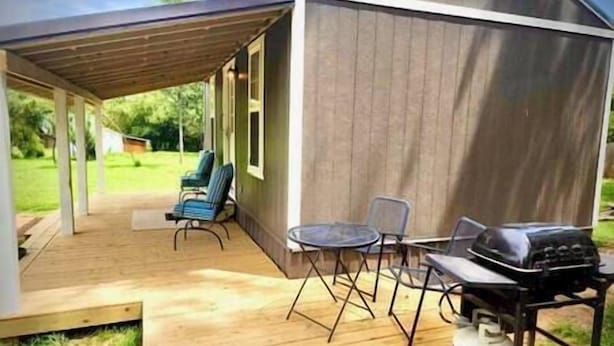 Un patio techado con mobiliario exterior y una parrilla.