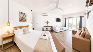 Una habitación de hotel con una cama grande, un sofá, una mesa de comedor y una televisión.