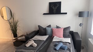 Et moderne soveværelse med seng, puder, et natbord, en lampe og et kunstværk på væggen.