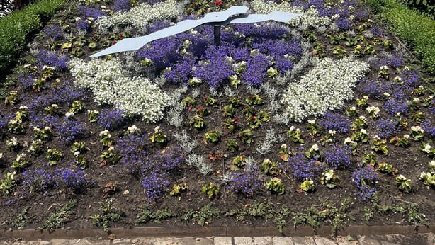 Et traditionelt bindingsværkshus med rødt tegltag og blomsterbed foran.