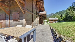 Una cabana de fusta amb terrassa, mobiliari exterior i vistes del paisatge circumdant.