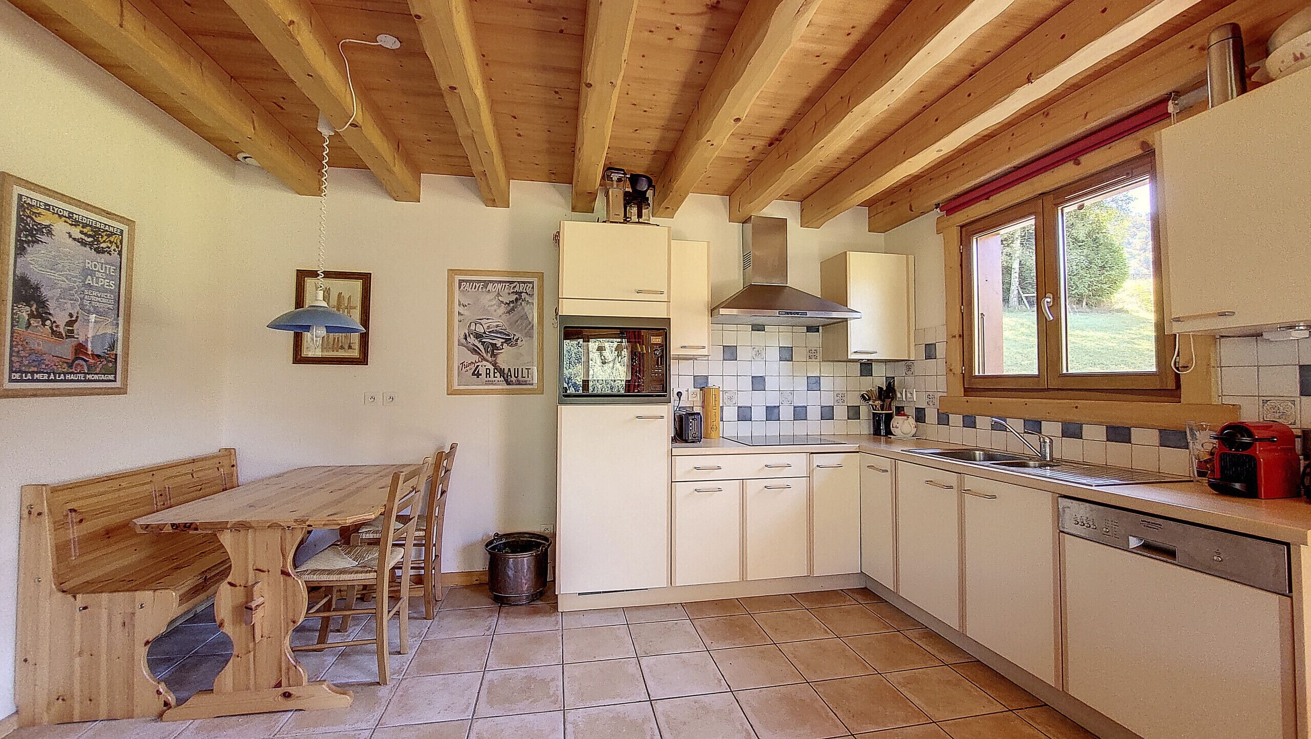 Una cocina con armarios de madera, salpicadero azulejado, un lavamanos y un ventanal.