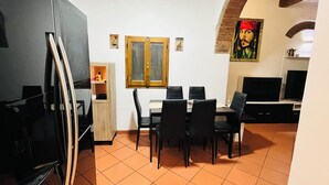 Cocina compacta con comedor, que incluye un refrigerador, un mueble de madera, una mesa de comedor con sillas y un televisor.