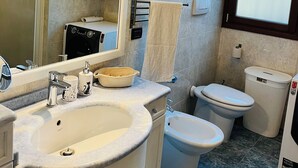 Un baño con un espejo grande, dos inodoros, un lavamanos y una ducha.