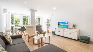 Un soggiorno moderno con un divano, poltrone, un tavolino da caffè e una TV su un mobile bianco.
