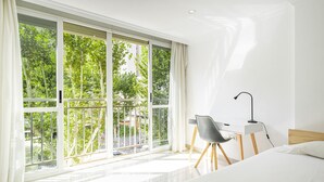 Una moderna camera d'albergo con una grande finestra, un letto, una scrivania e una sedia.