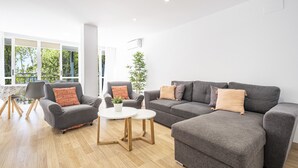 Una sala de estar moderna con un sofá gris, dos sillones, una mesa de centro y una planta en maceta.