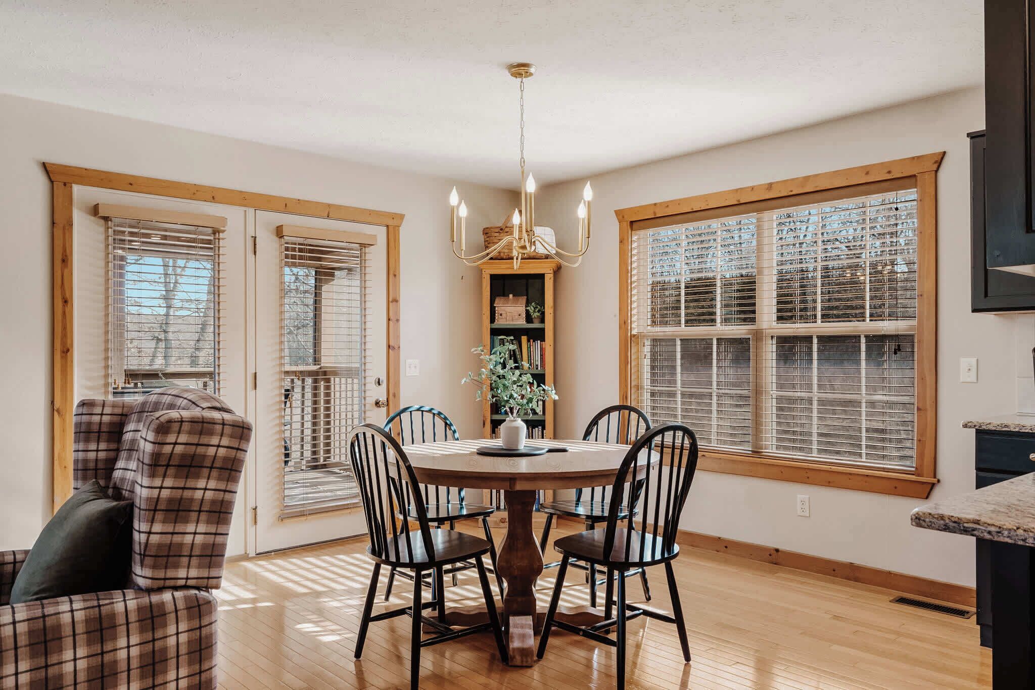 A dining area with a round wooden table, four chairs, and a chandelier.