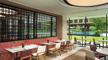 A restaurant with a long counter, cushioned seating, and a view of a swimming pool.