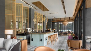 A modern kitchen with a bar area, seating with a view, and a dining area with tables and chairs. - Courtyard by Marriott Bangkok Suvarnabhumi Airport (Bangkok)