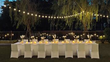 An outdoor dining area with string lights, white tablecloths, and candles.