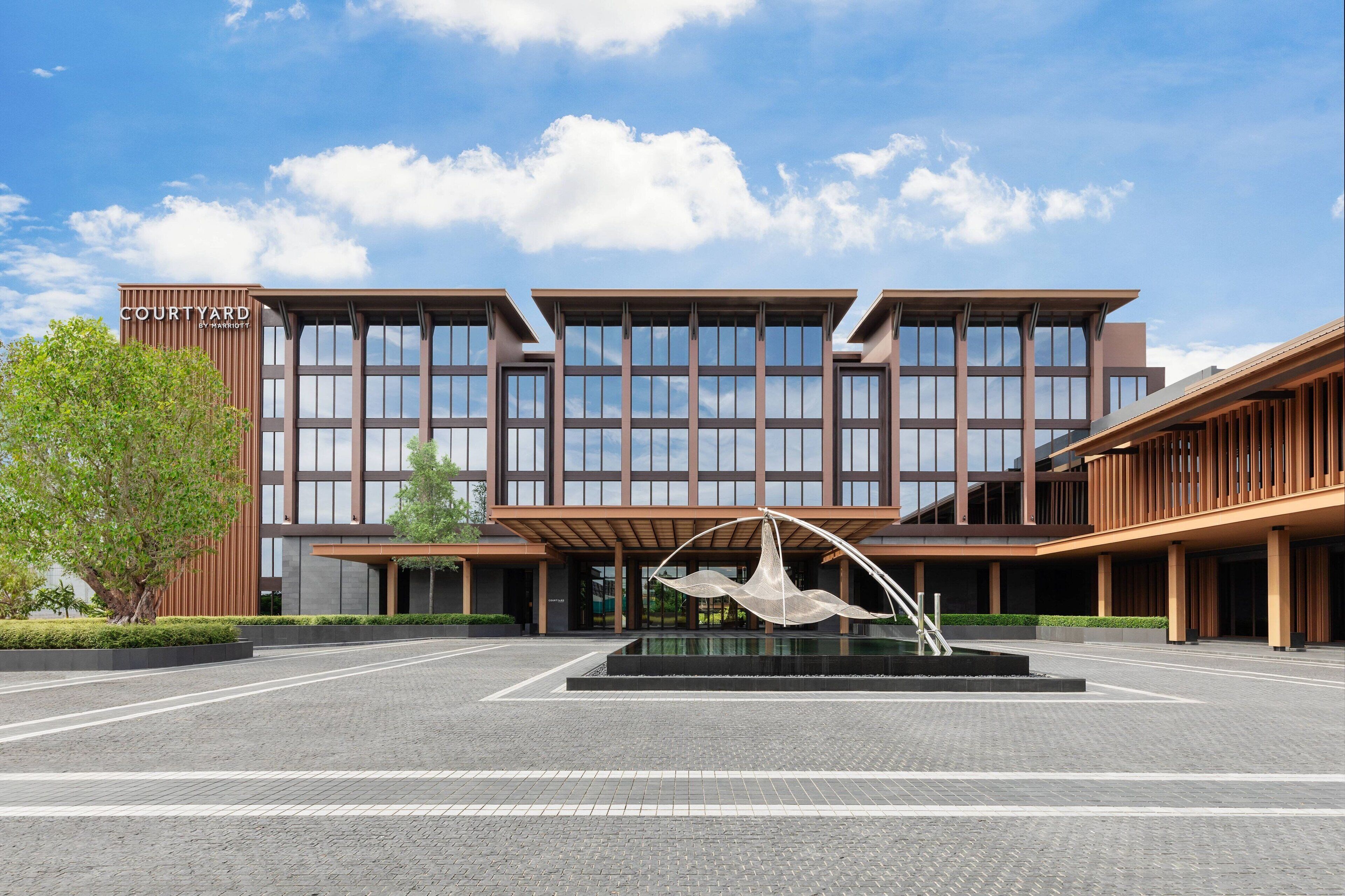 A modern building with a courtyard, large windows, and a sculpture.