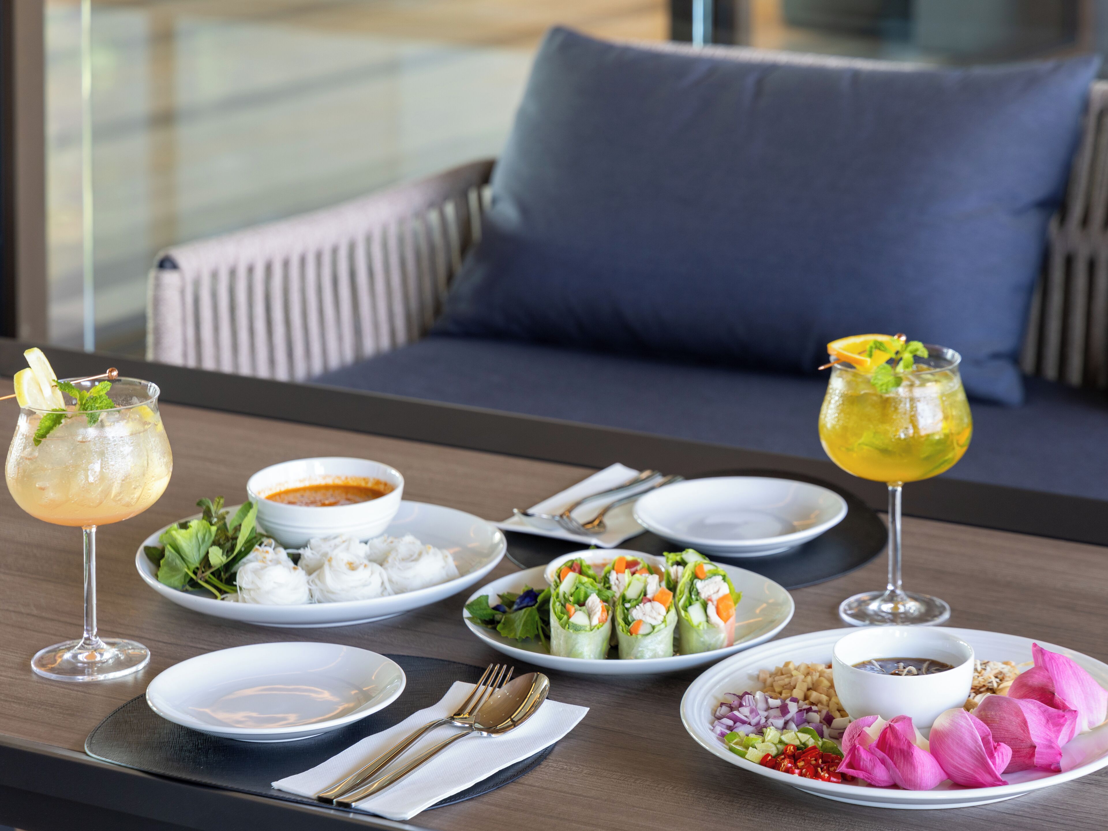 A dining table with various dishes, including a salad, soup, and a drink, set for a meal.