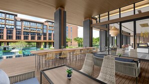A modern outdoor seating area with a pool view, wooden deck, and contemporary furniture. - Courtyard by Marriott Bangkok Suvarnabhumi Airport (Bangkok)