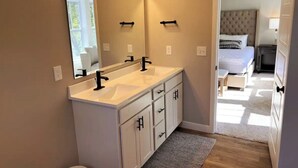 A modern bathroom with a double sink, a large mirror, and a view into the bedroom. - SoHappy Haven - 6 bdrm, Game Room, Year Round Pools, Hot Tub, Marina & Clubhouse (South Haven)