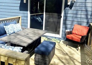 Relax on the patio with a wooden table, wicker bench, and cushioned chair.