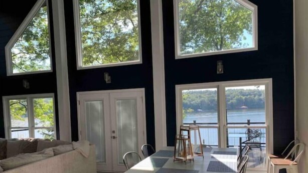 Une pièce spacieuse avec une grande table à manger, un canapé et une vue sur un lac.