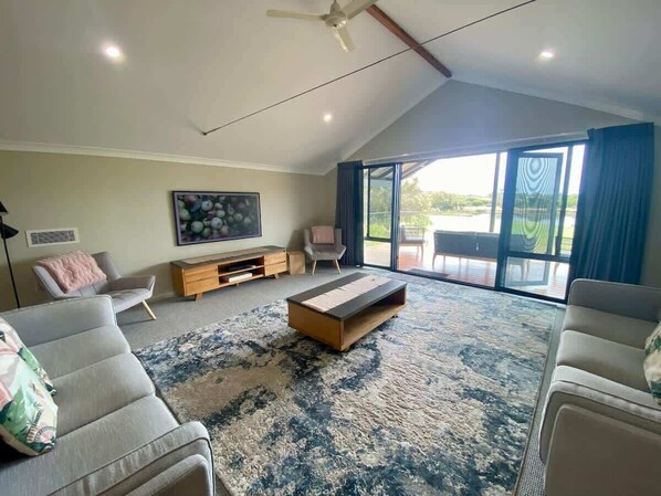 A spacious living room with a large window, a ceiling fan, and a coffee table.
