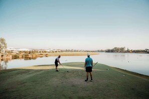 Ein Golfplatz mit einem Wasserkörper im Hintergrund.
