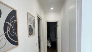 Un couloir étroit doté d’un plancher en bois, de murs blancs et de deux œuvres d’art abstraites encadrées.