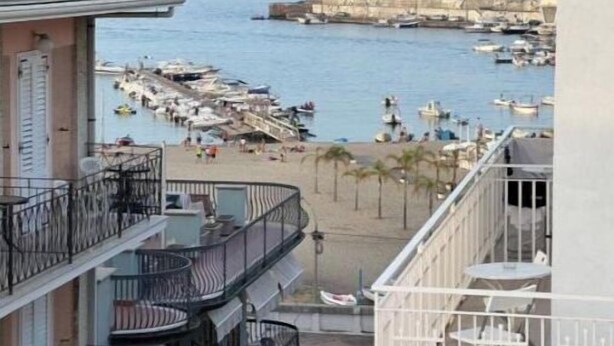 Un hôtel à plusieurs étages doté de balcons donnant sur une marina et une plage.
