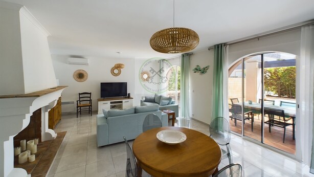 Un salon moderne avec un canapé, un téléviseur et une table à manger avec des chaises.