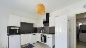 Une cuisine de taille réduite, avec des meubles blancs, un four à micro-ondes, un lave-vaisselle et une cuisinière.