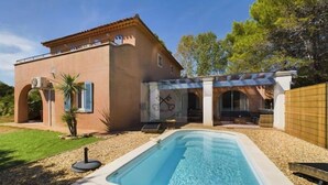 Une maison avec une piscine, une pergola et un jardin.