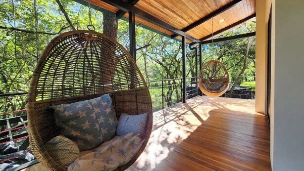 A spacious room with a hanging chair and a swing chair, large windows offering a view of trees, and a wooden floor. - Casa Vail, surrounded by jungle in Nosara area (Nosara)